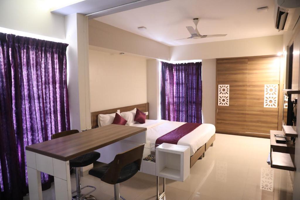 a bedroom with a bed and a desk and a table at AUHTEL Baner in Pune