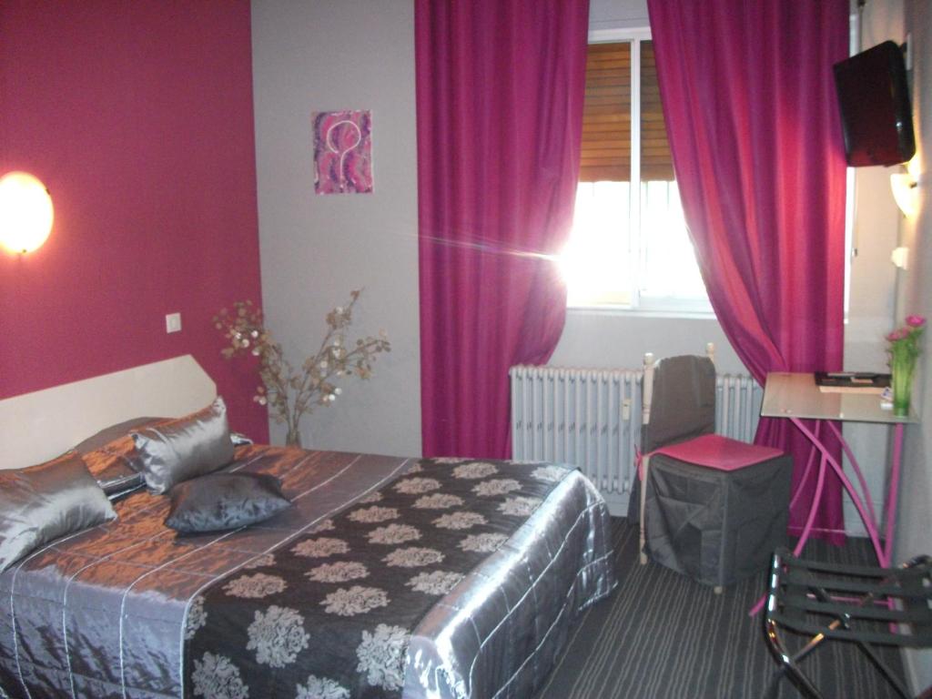 ギャップにあるオテル ル ミシュレの紫の壁のベッド1台、テレビが備わるベッドルーム1室が備わります。
