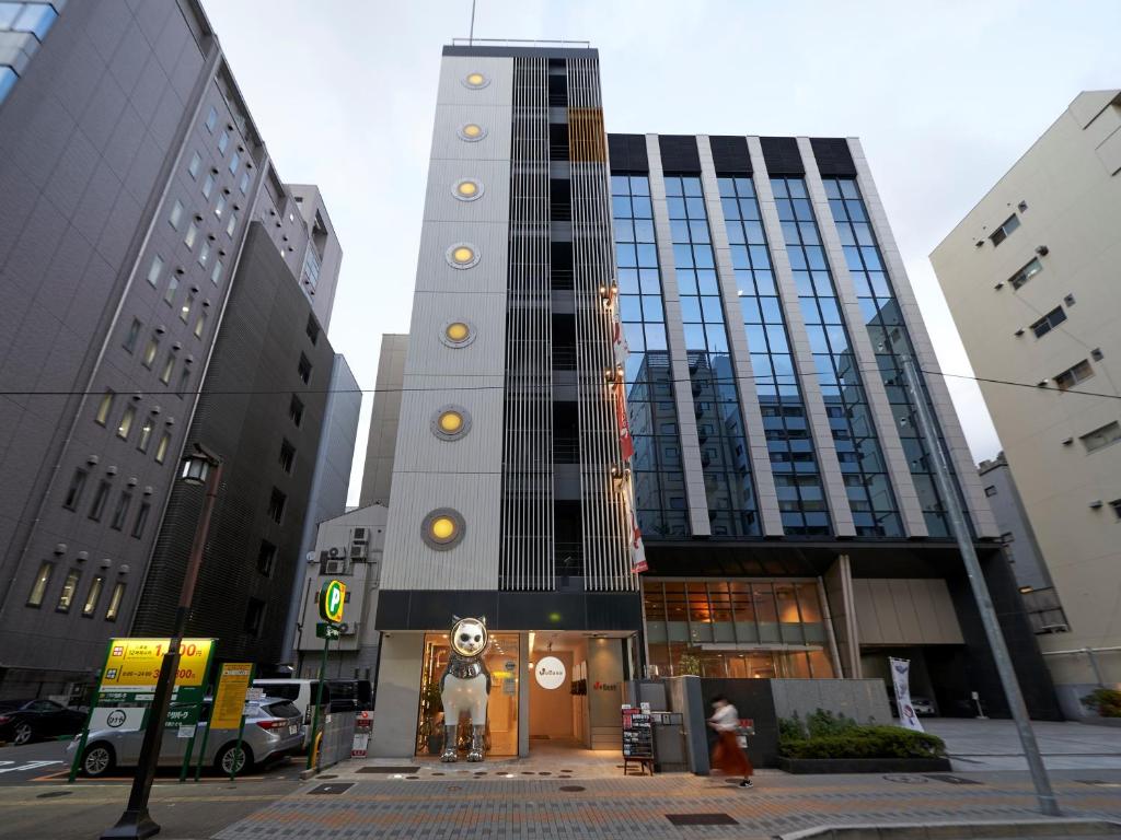 een hoog gebouw met een standbeeld ervoor bij WeBase Hakata Hostel in Fukuoka