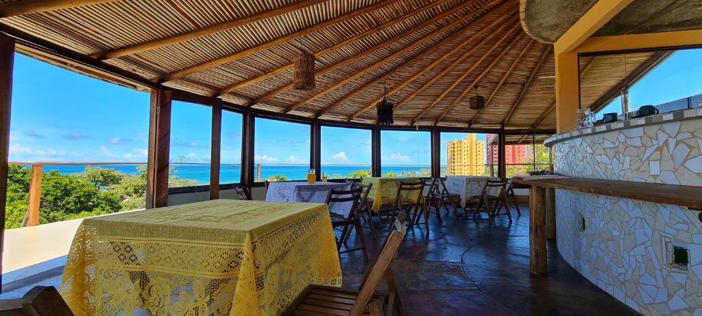 comedor con mesa, sillas y ventanas en Pousada Bodega da Terra, en Pirangi do Norte