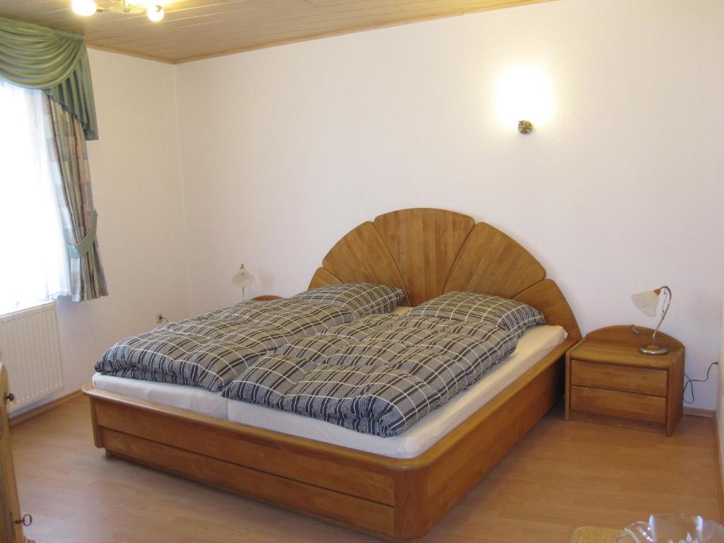 a bedroom with a bed with a wooden head board at Ferienwohnungen - An der Kunstakademie in Heimbach