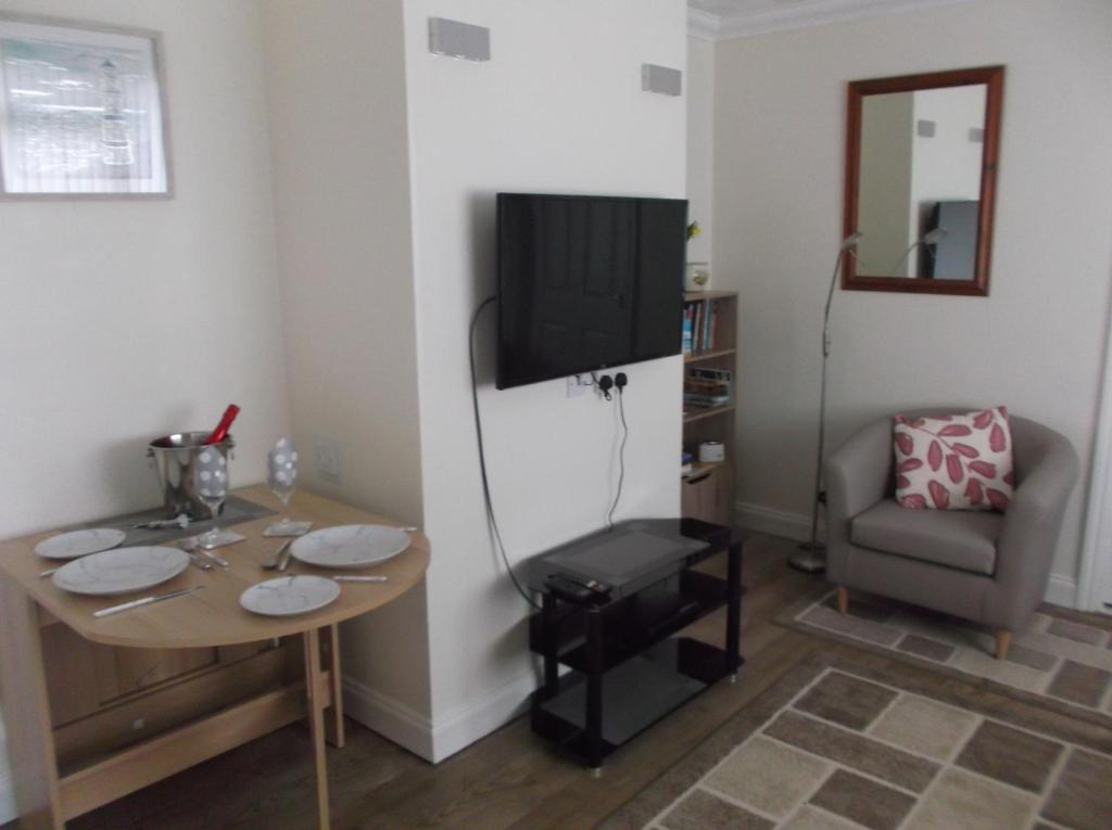 a room with a table and a television and a chair at Sea Shells in Greatstone