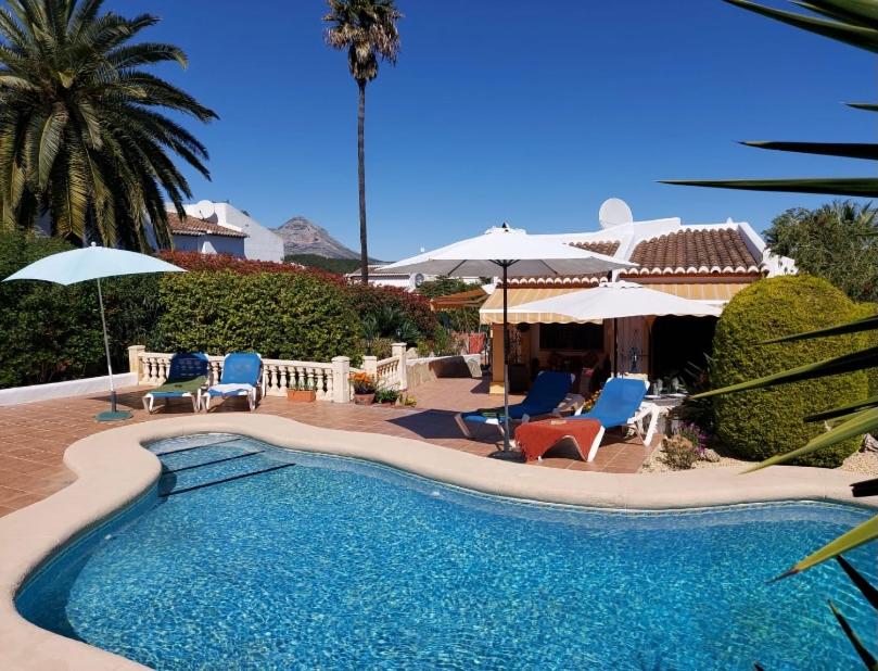 una piscina con sillas y sombrillas en Cassandra - Beautiful Private Villa with Heated Pool included, en Jávea
