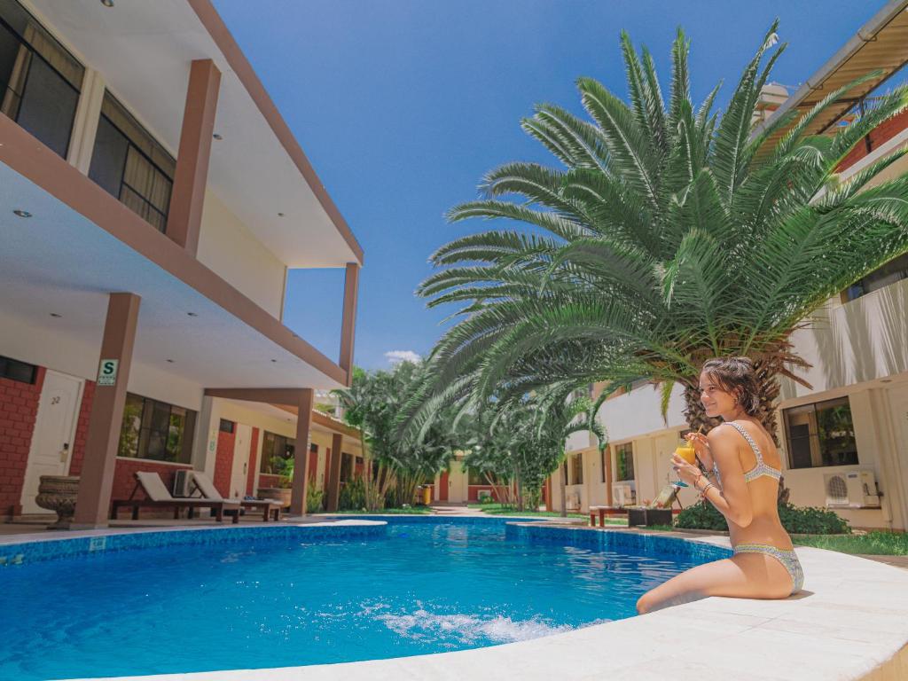 une femme en bikini assise à côté d'une piscine dans l'établissement El Angolo Piura, à Piura