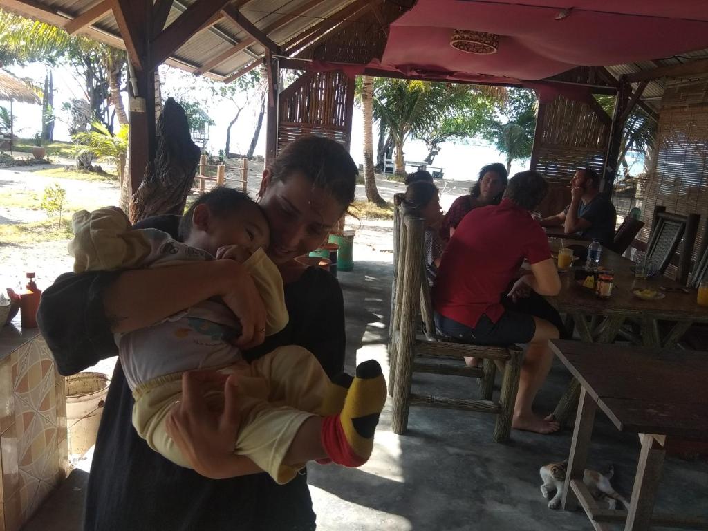 a man holding a child in his arms at Asari Timo Cottage in Karimunjawa