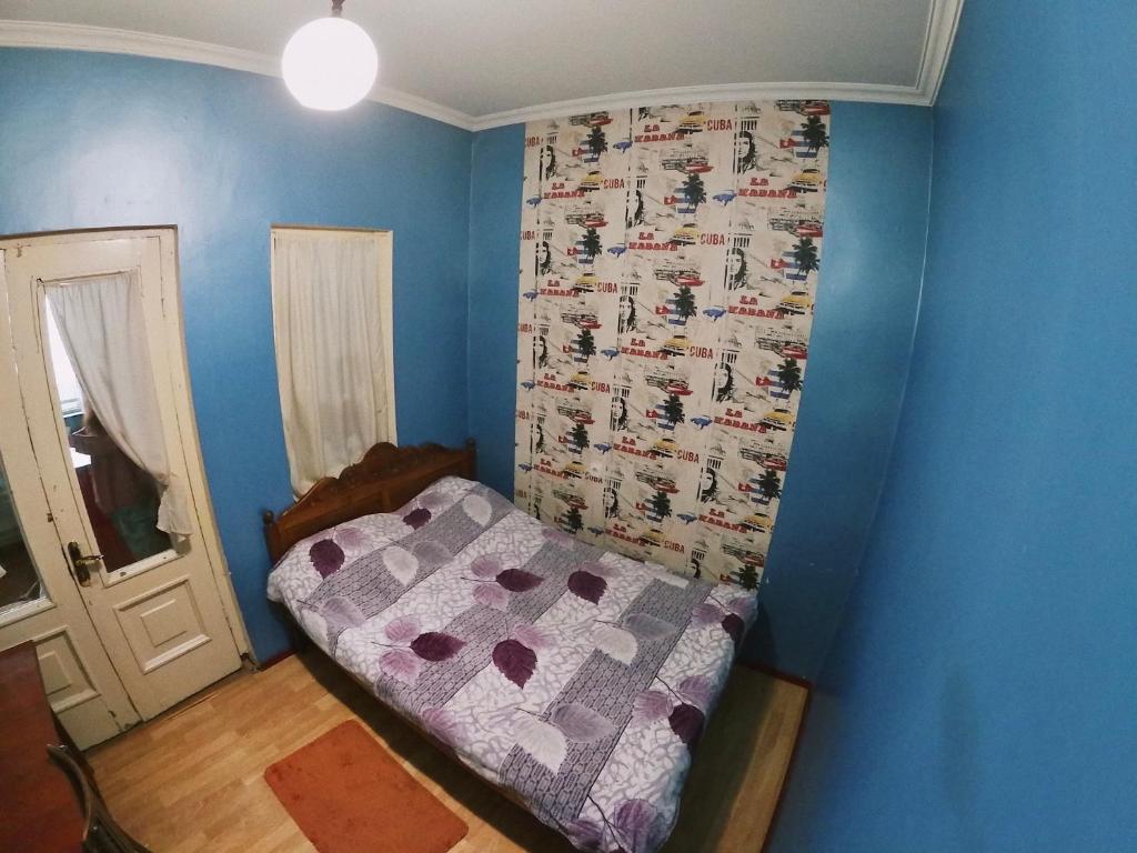 Habitación pequeña con cama y pared azul en Valera Homestay en Tiflis
