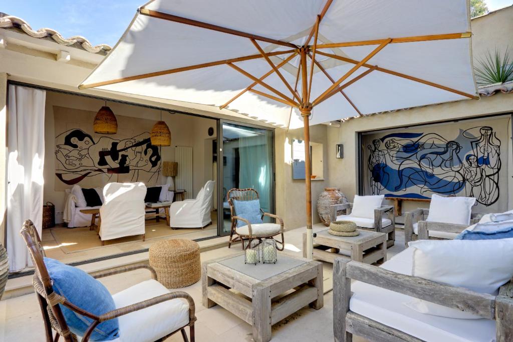 a patio with chairs and an umbrella at Le Bastidon de PAMPELONNE in Saint-Tropez