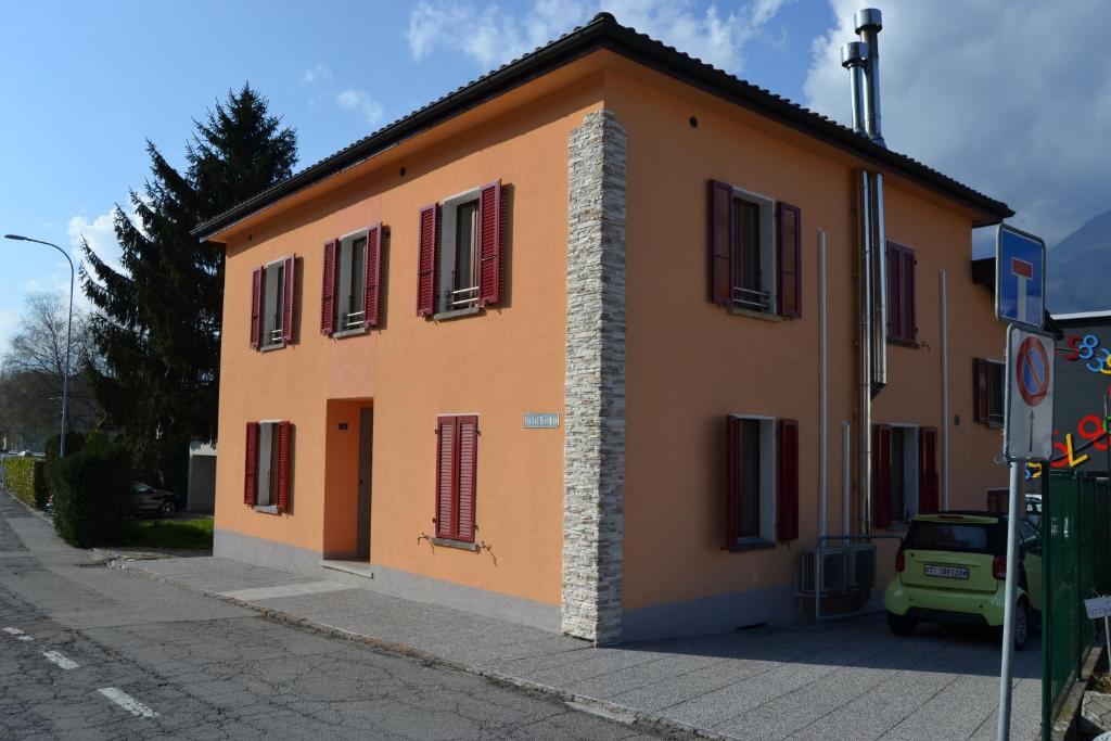 a orange building with red shutters on a street at Casa Yoghi in Cadenazzo