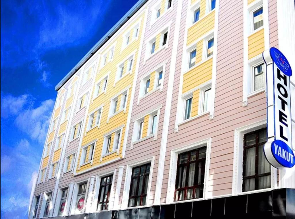 un edificio blanco y amarillo con un cartel delante en Hotel Yakut en Van