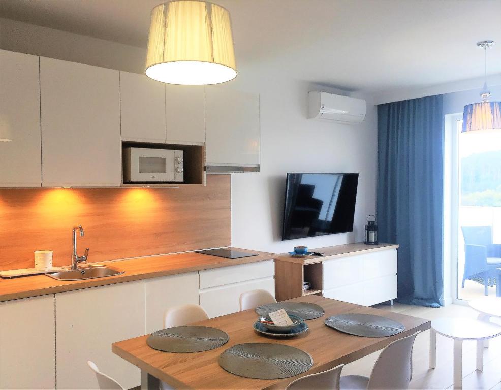 kuchnia z drewnianym stołem i jadalnią w obiekcie Apartament Diuna w Grzybowie