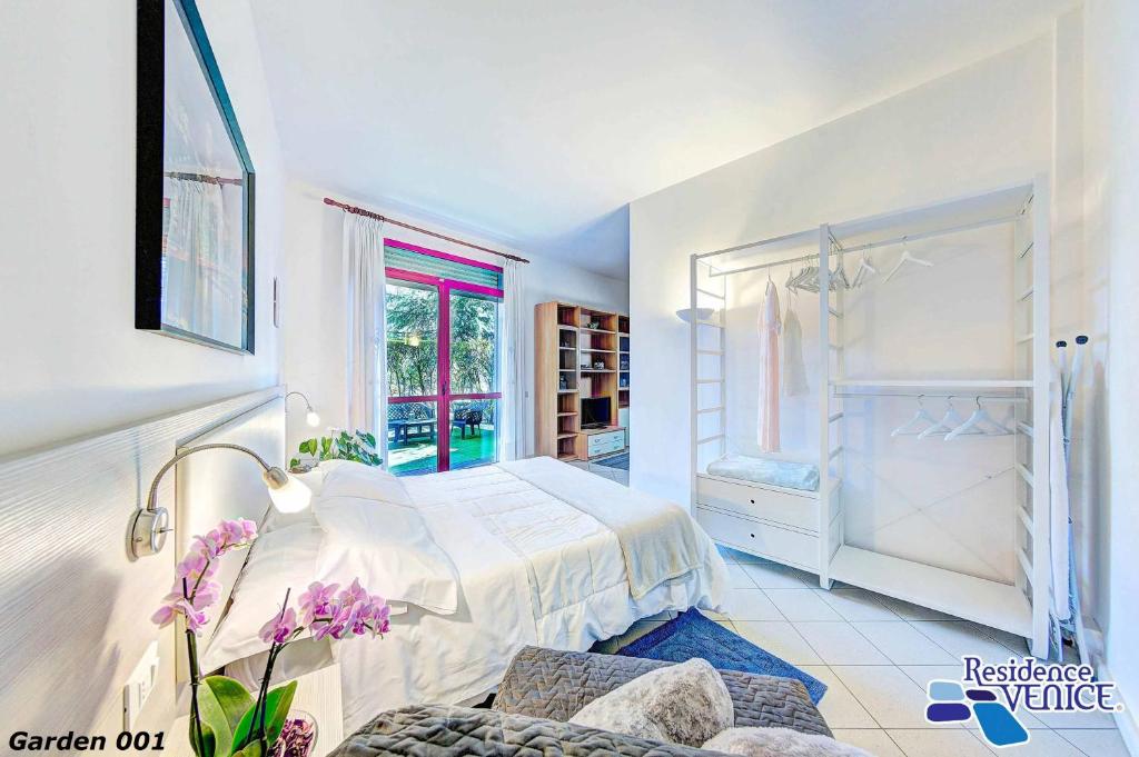 a white bedroom with a bed and a window at Venice Aparthotel in Quarto dʼAltino