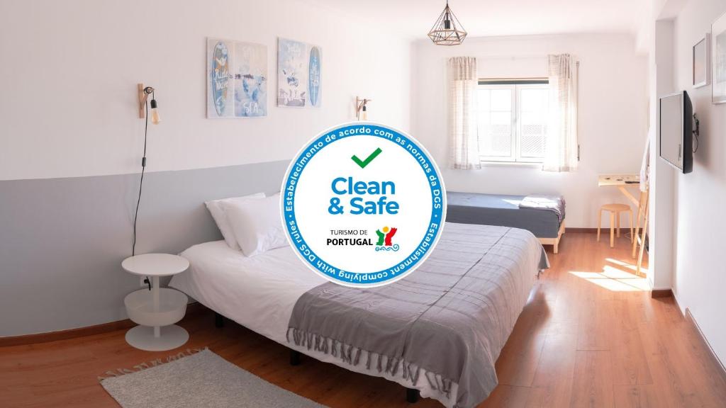 een kamer met een bed met een bord dat schoon en veilig leest bij Perfect Shore Guest House in Baleal