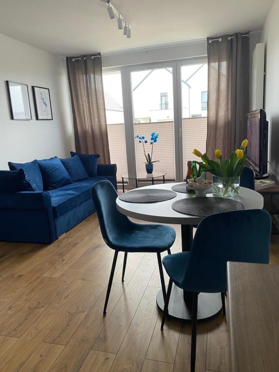 a living room with a blue couch and a table and chairs at Apartament Wiczlino in Gdynia