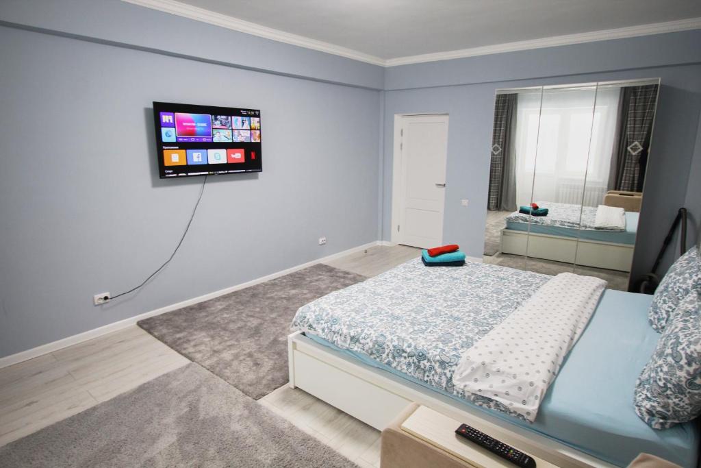 sypialnia z łóżkiem i telewizorem na ścianie w obiekcie Нурсая#2 w mieście Atyrau