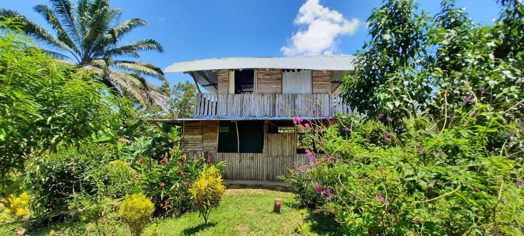 ein Holzhaus mit einem Balkon im Garten in der Unterkunft La Muñequita Lodge 1 - culture & nature experience in Palmar Norte