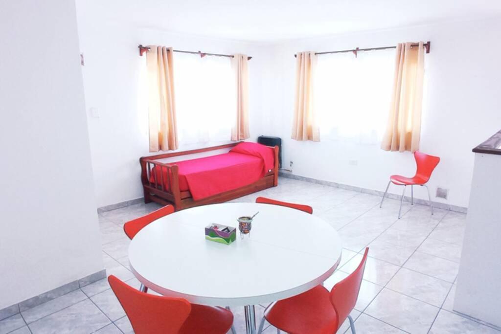 ein Wohnzimmer mit einem weißen Tisch und roten Stühlen in der Unterkunft Newen in El Calafate