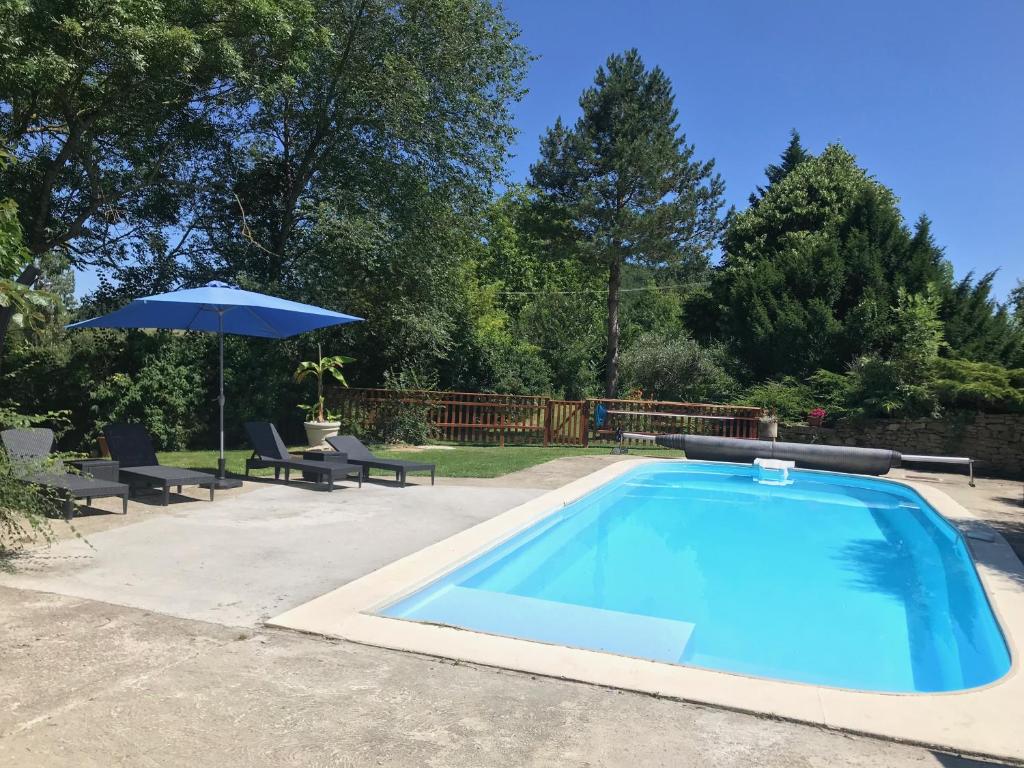 a swimming pool with an umbrella and chairs and a table and an umbrella at Gîtes de Montcabirol - Malepère in La Bastide-de-Bousignac