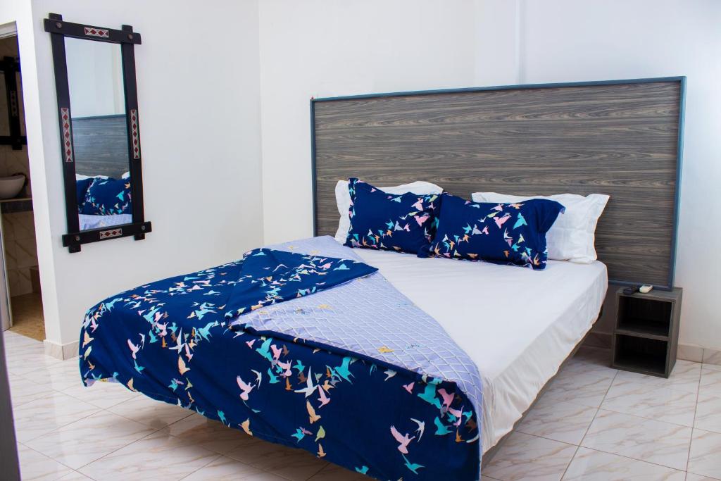 una camera da letto con un letto con piumone e cuscini blu di Van Der Salle - Flovan Plaza a Haatso