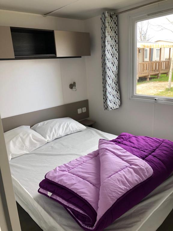 a bed with a purple blanket on it in a bedroom at GRS Mobil Home in Onzain