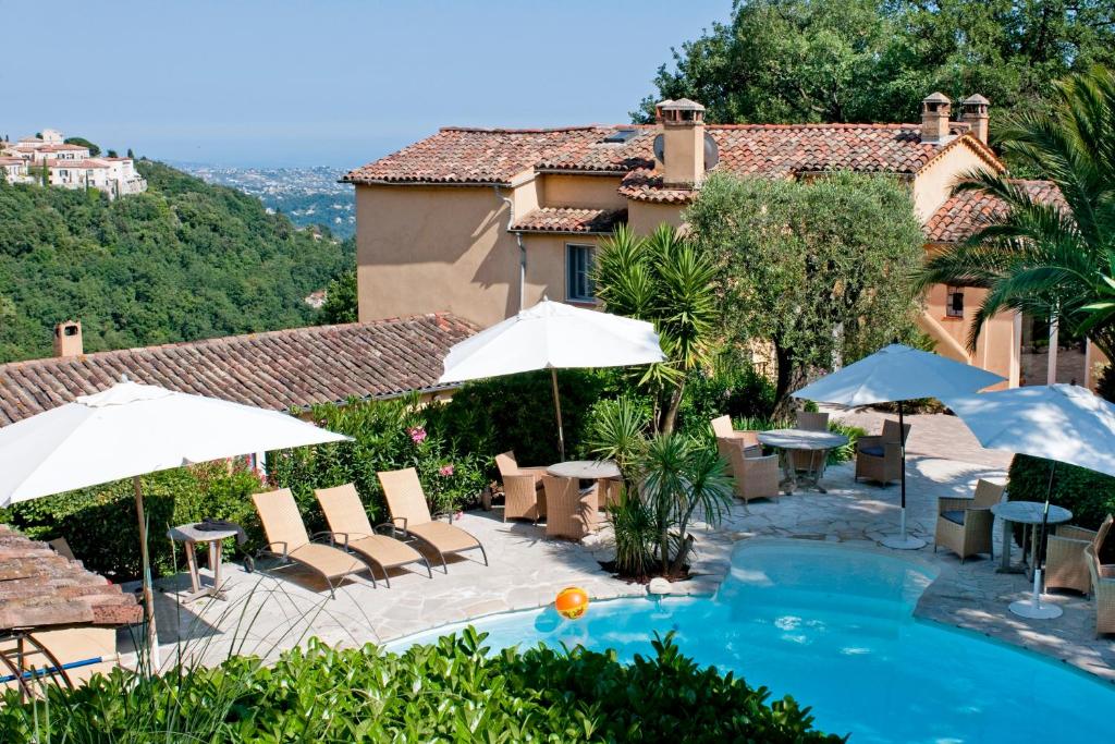 a pool with chairs and umbrellas and a house at La Colline de Vence in Vence