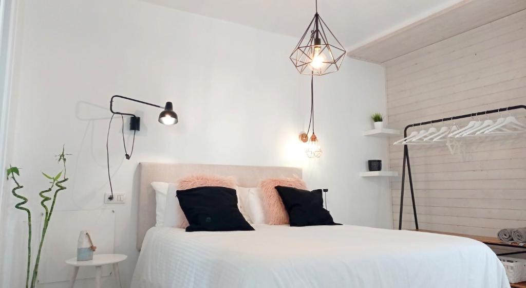 um quarto branco com uma cama branca com almofadas pretas em Divine em Puerto del Carmen
