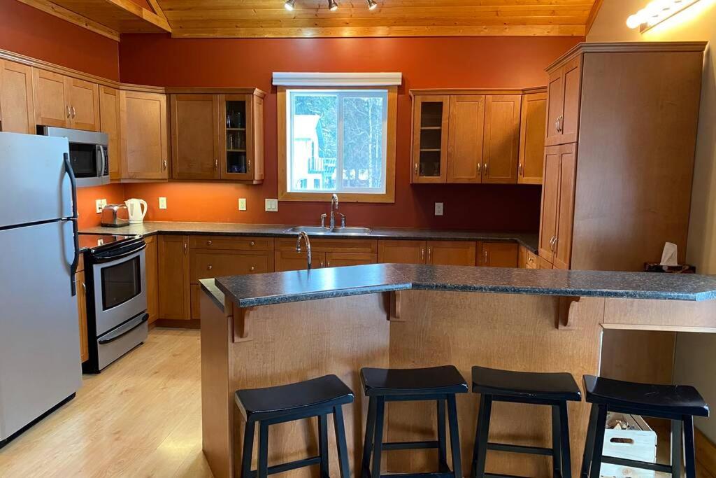 eine Küche mit Holzschränken und eine große Insel mit Barhockern in der Unterkunft Gudjonson Getaway - 2 bed 2 bath Cabin in Golden