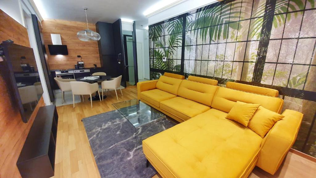 uma sala de estar com um sofá amarelo e uma sala de jantar em The Main Square Apartments em Banja Luka
