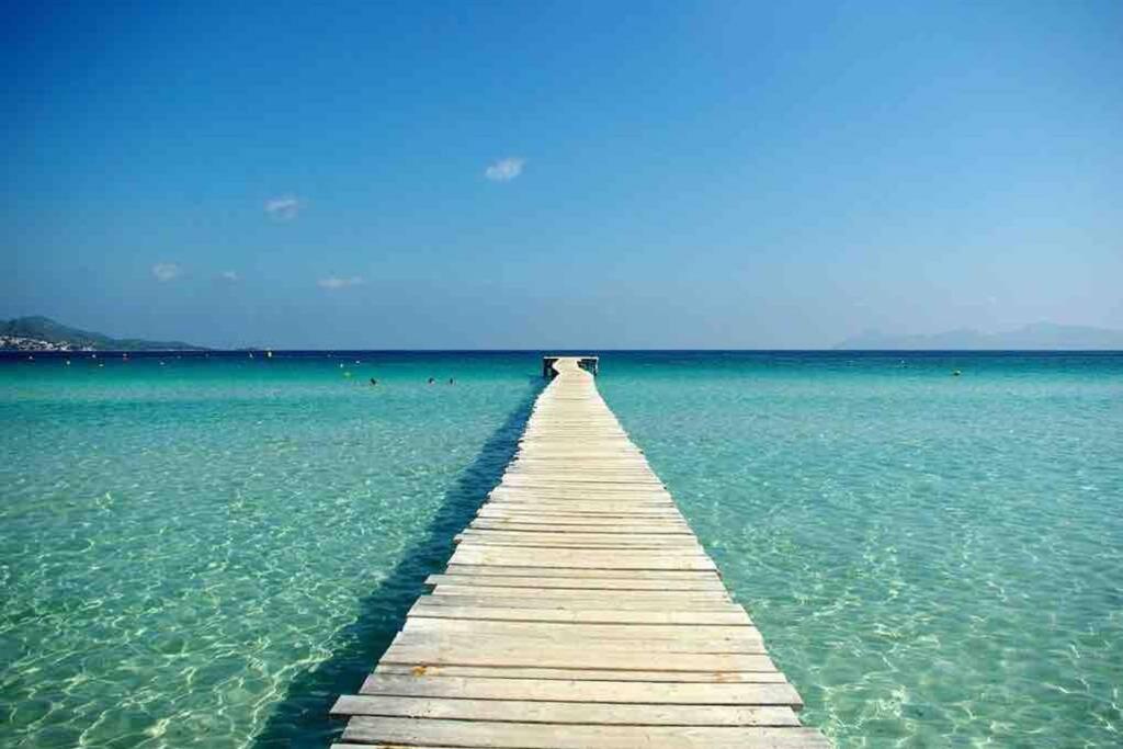 a wooden pier in the middle of the water at Amazing house close to the beach in Port d'Alcudia