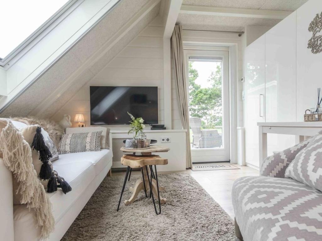 a living room with a white couch and a tv at Vakantiewoningen Prelude & Etude in Wieringerwaard