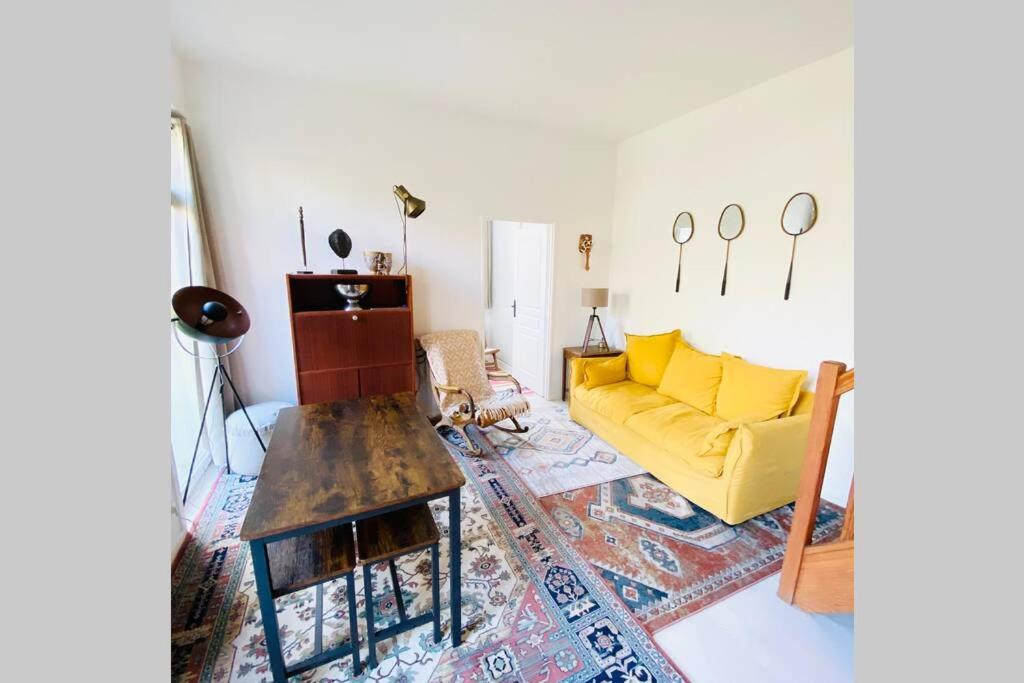uma sala de estar com um sofá amarelo e uma mesa em Proche Golf Appartement 4pers avec parking piscine tennis em Neufchâtel-Hardelot