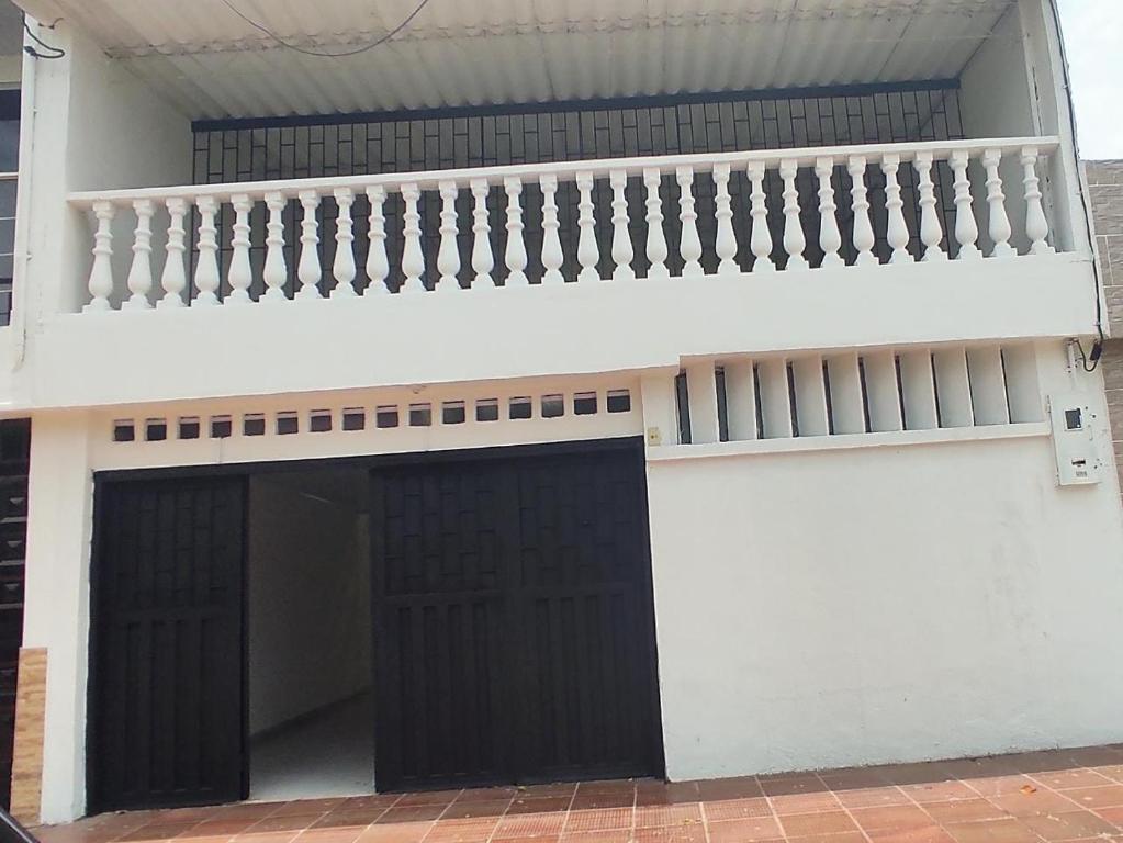 a white building with black doors and a balcony at Casa con piscina privada in Girardot