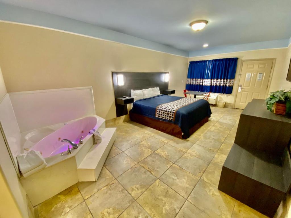 a hotel room with a bed and a bath tub at Texas Inn & Suites McAllen at La Plaza Mall and Airport in McAllen