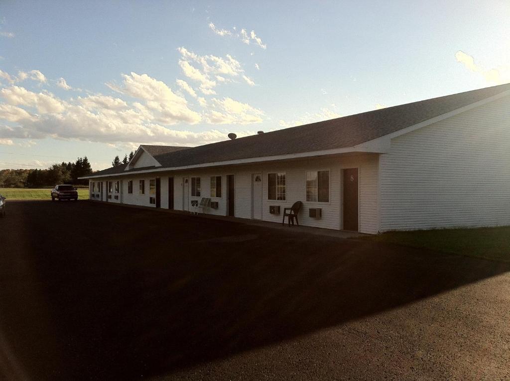 Un bâtiment blanc avec une voiture garée devant. dans l'établissement Village Inn Motel, à Chatham