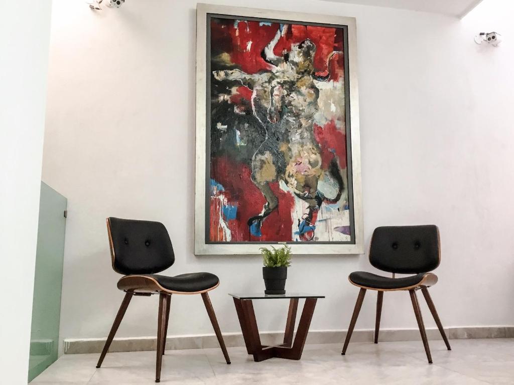 two chairs in a room with a painting on the wall at Hotel MAC7 in Aguascalientes