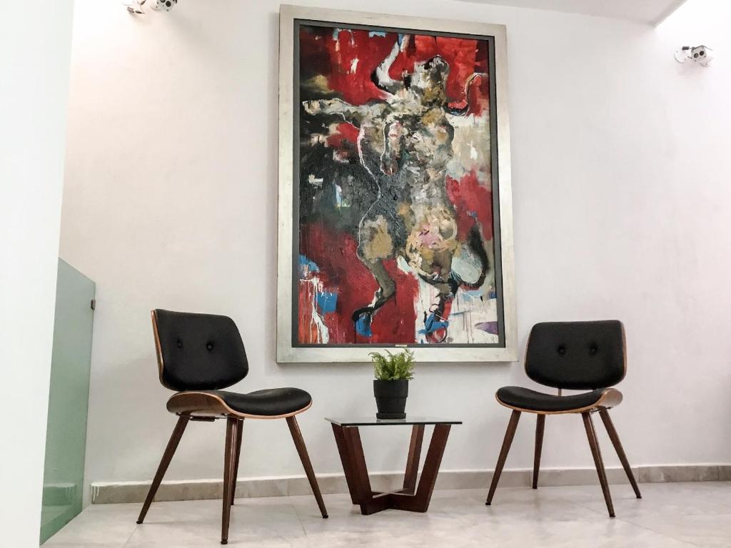 Deux chaises dans une pièce avec un tableau sur le mur dans l'établissement Hotel MAC7, à Aguascalientes