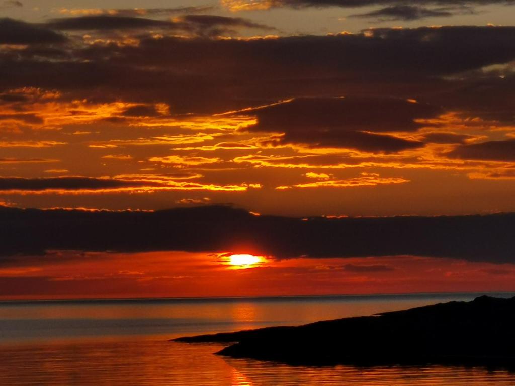 a sunset over the ocean with the sun setting at Kongsfjord Paradise Holiday in Kongsfjord