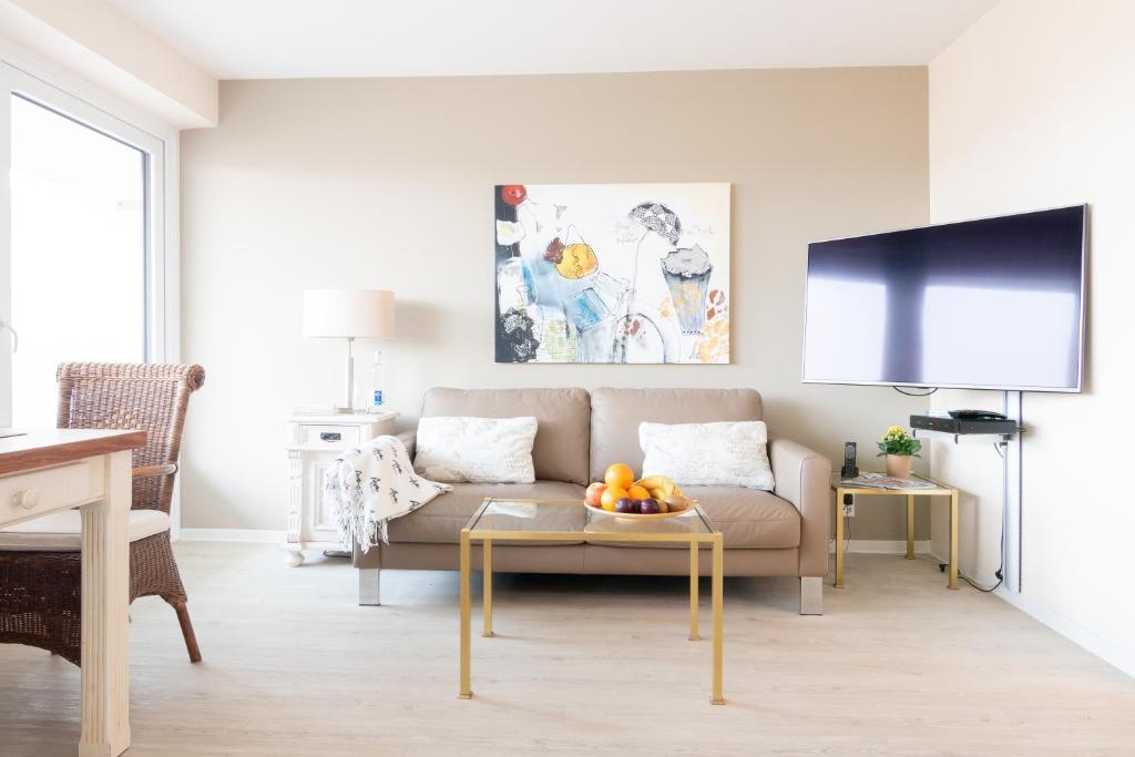 ein Wohnzimmer mit einem Sofa und einem TV in der Unterkunft Premium Appartement Rosenmöwe Sylt in Wenningstedt-Braderup