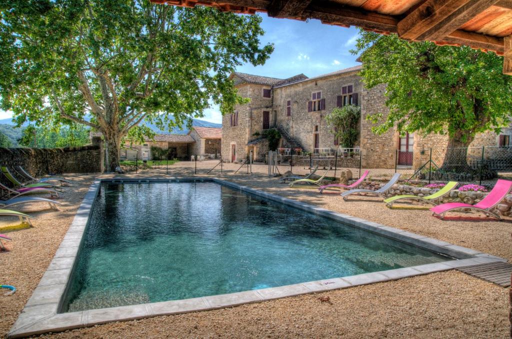 - une piscine avec des chaises longues devant un bâtiment dans l'établissement Gîtes du Domaine des Dames, à Vallon-Pont-dʼArc