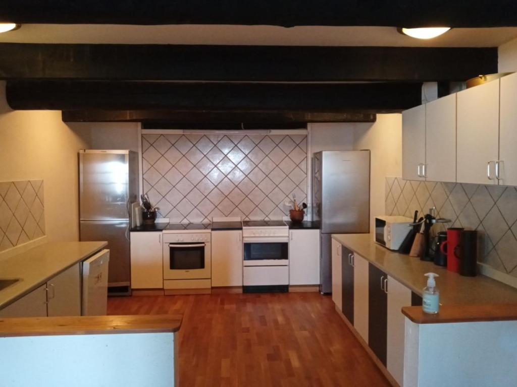 uma grande cozinha com electrodomésticos brancos e pisos em madeira em Store Lærkegård em Allinge