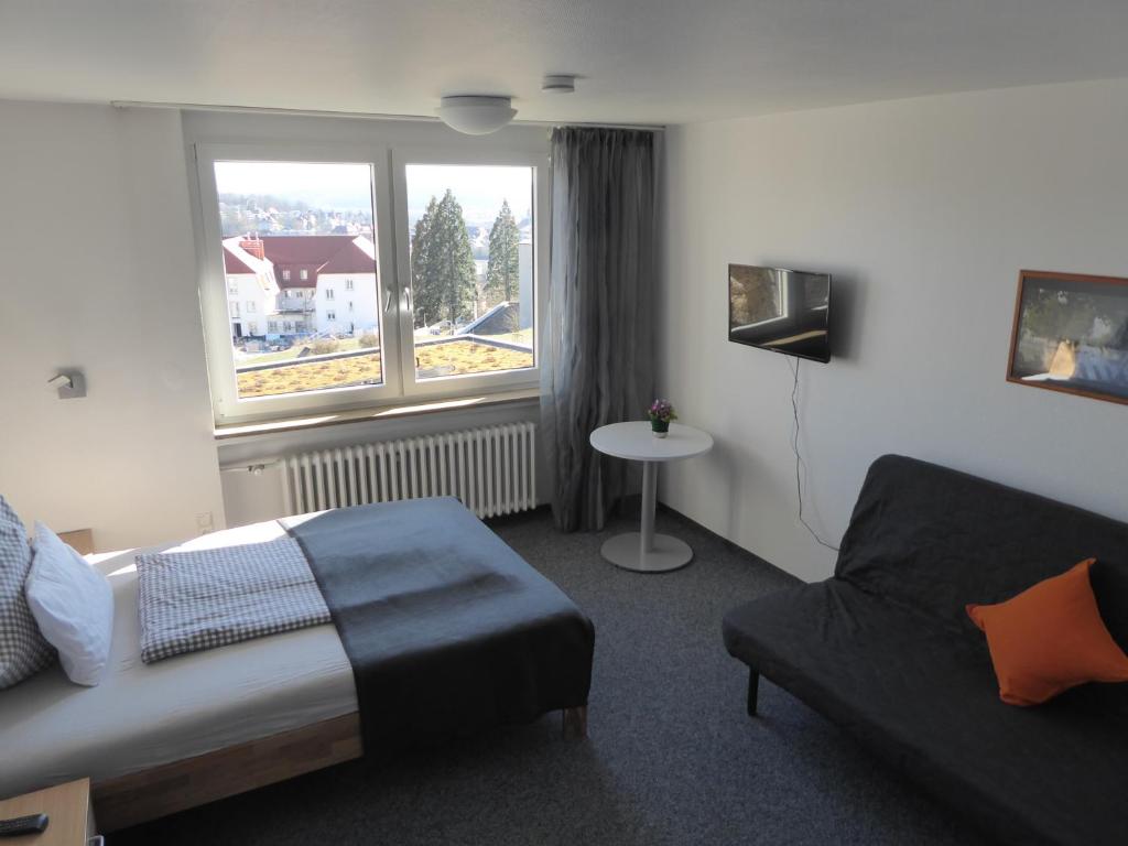 ein Schlafzimmer mit einem Bett, einem Sofa und einem Fenster in der Unterkunft Ferienwohnung Zollernblick in Tübingen