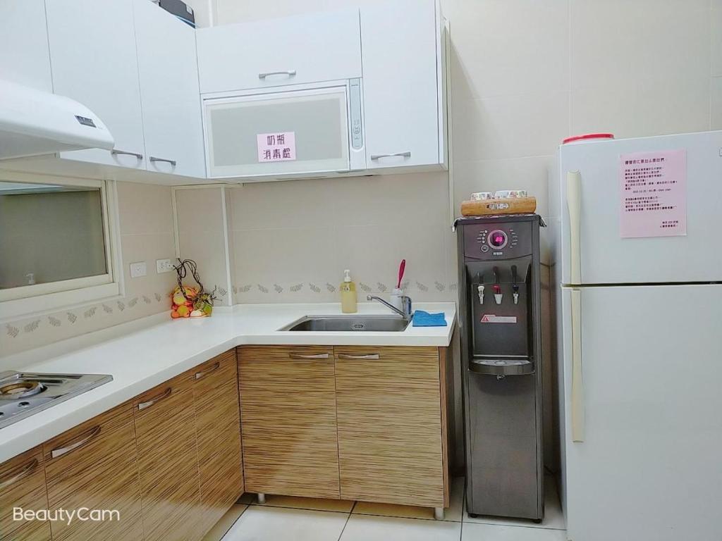 a small kitchen with a refrigerator and a sink at Nan Jing 222 Homestay in Hualien City