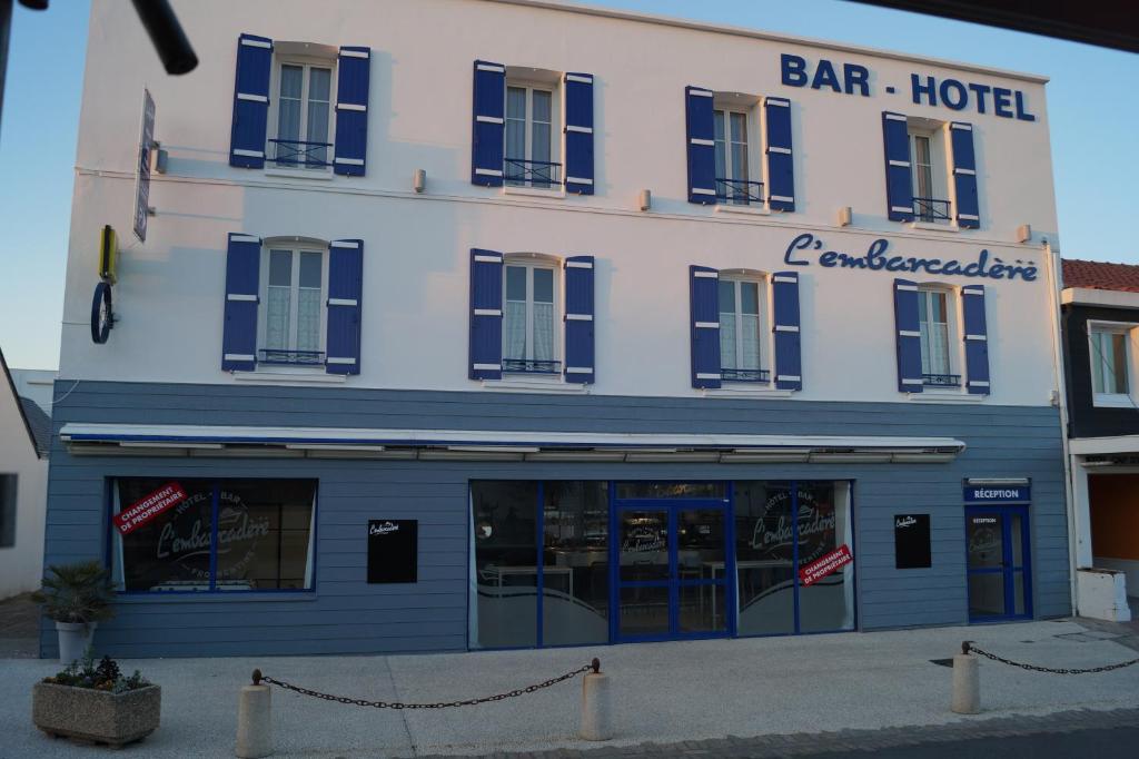 a blue and white building with a bar hotel at Hôtel L'Embarcadère in La Barre-de-Monts