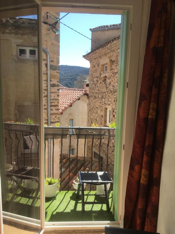 d'une fenêtre donnant sur un balcon avec une table. dans l'établissement La Petite Adresse de Rose Maison de vacances Entrée autonome, à Le Poujol-sur-Orb