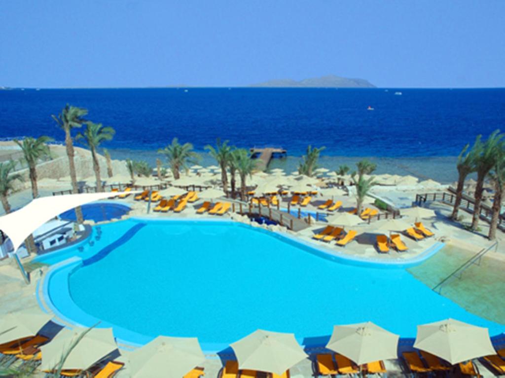 uma grande piscina com guarda-sóis e o oceano em Xperience Sea Breeze Resort em Sharm El Sheikk