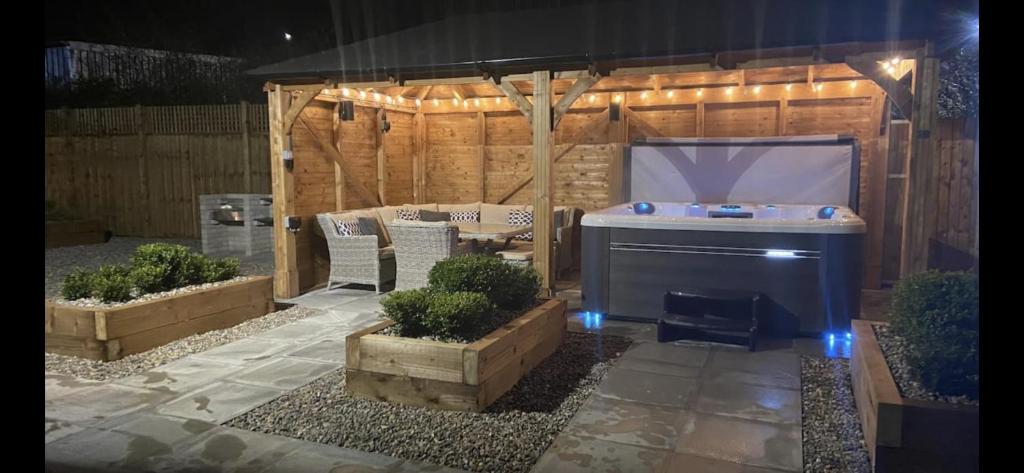 einen Hinterhof mit Grill und einigen Pflanzen und Lichtern in der Unterkunft Rhos Walia,near Snowdonia,Hot tub in Caernarfon