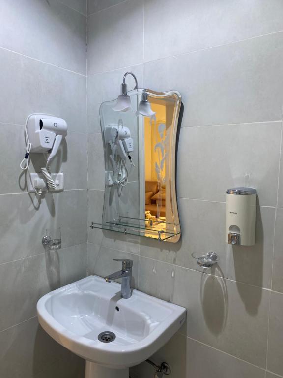 ein Bad mit einem Waschbecken und einem Spiegel in der Unterkunft شقق شاطئ النخيل in Umm Lajj