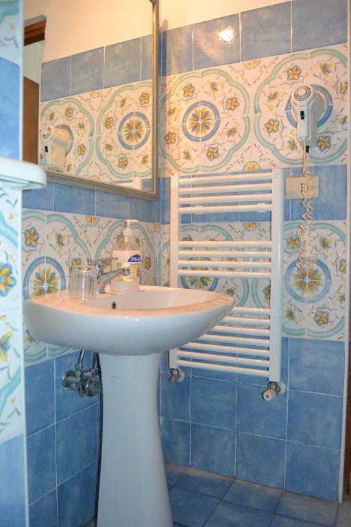 a bathroom with a white sink and blue tiles at Piccolo Tirreno Hotel Residence in Procida