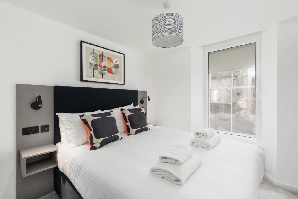 a white bedroom with a large bed with towels on it at Destiny Scotland Market Street Apartments in Edinburgh
