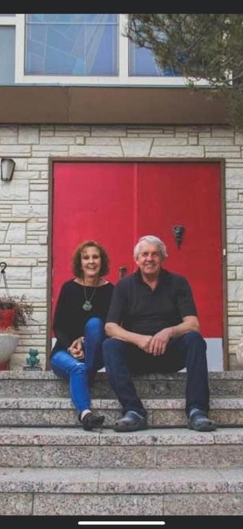 a man and woman sitting on steps in front of a red door at The Old Church B&B in Warner