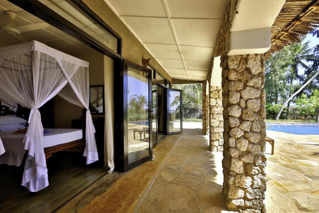 a bedroom with a bed with curtains and a pool at Tamani Villas in Matemwe